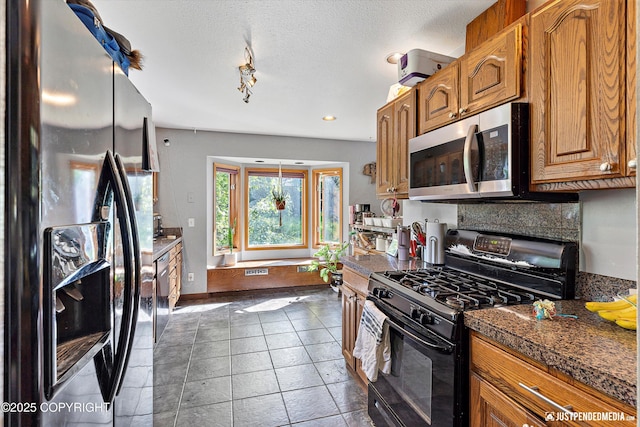 2020 N Kentucky Derby Dr, Palmer, AK 99645 - kitchen with fridge with ice dispenser, black gas range, stainless steel microwave, dark countertops, and brown cabinetry