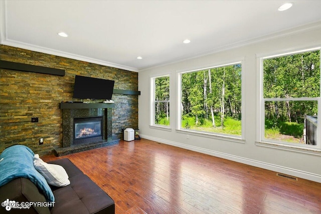 4920 W Fairview Loop, Wasilla, AK 99654 - unfurnished living room featuring plenty of natural light, crown molding, a stone fireplace, wood finished floors, and recessed lighting