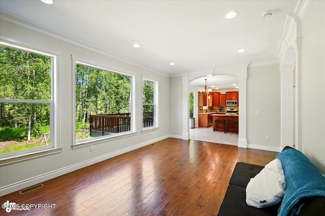 4920 W Fairview Loop, Wasilla, AK 99654 - living area featuring decorative columns, plenty of natural light, crown molding, wood-type flooring, and a chandelier
