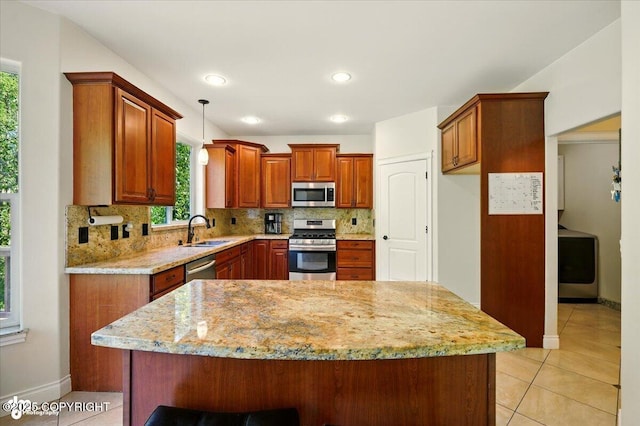 4920 W Fairview Loop, Wasilla, AK 99654 - kitchen with stainless steel appliances, tasteful backsplash, washer / clothes dryer, brown cabinets, and light stone countertops