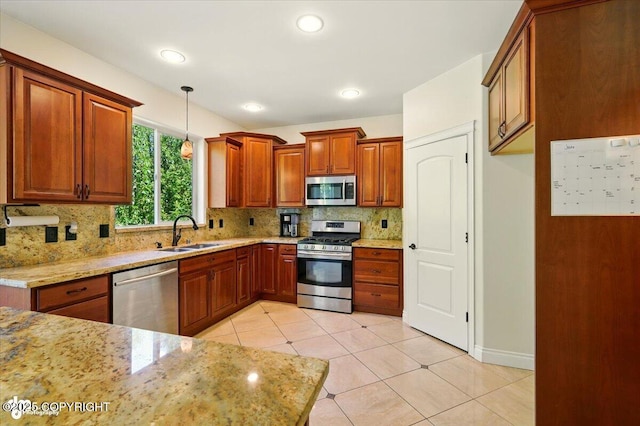 4920 W Fairview Loop, Wasilla, AK 99654 - kitchen with stainless steel appliances, tasteful backsplash, decorative light fixtures, brown cabinetry, and light stone countertops