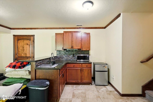 4920 W Fairview Loop, Wasilla, AK 99654 - kitchen featuring appliances with stainless steel finishes, backsplash, brown cabinets, a peninsula, and crown molding