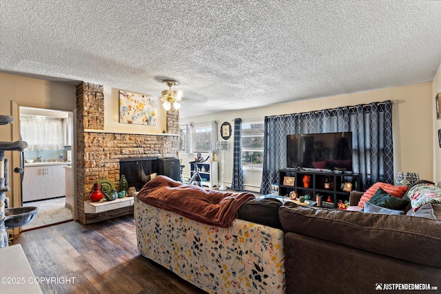 4417 San Roberto Ave, Anchorage, AK 99508 - living room featuring wood finished floors, ceiling fan, a stone fireplace, baseboard heating, and a textured ceiling