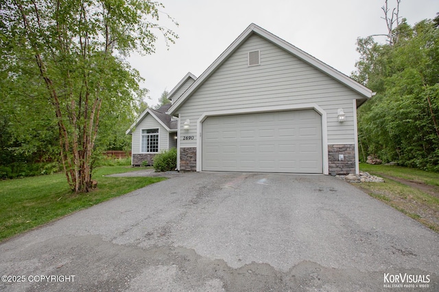 2690 E Tamarak Ave, Wasilla, AK 99654 - view of front of home featuring stone siding, driveway, a front lawn, and a garage