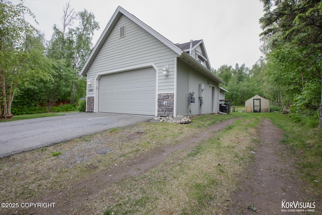 2690 E Tamarak Ave, Wasilla, AK 99654 - view of property exterior with asphalt driveway, stone siding, and an attached garage