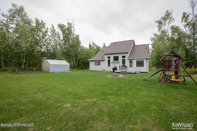 2690 E Tamarak Ave, Wasilla, AK 99654 - back of house with a yard, a shingled roof, an exterior structure, an outbuilding, and a playground