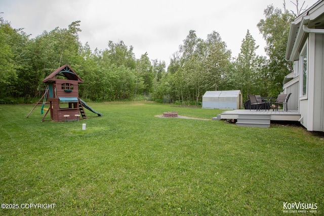 2690 E Tamarak Ave, Wasilla, AK 99654 - view of grassy yard with a wooden deck, a playground, a greenhouse, and an outdoor structure