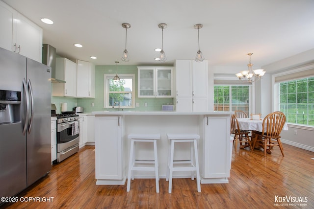 2690 E Tamarak Ave, Wasilla, AK 99654 - kitchen with appliances with stainless steel finishes, wall chimney exhaust hood, wood finished floors, tasteful backsplash, and recessed lighting