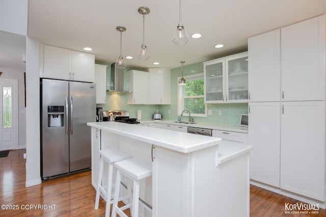 2690 E Tamarak Ave, Wasilla, AK 99654 - kitchen featuring appliances with stainless steel finishes, a sink, wall chimney exhaust hood, tasteful backsplash, and white cabinets