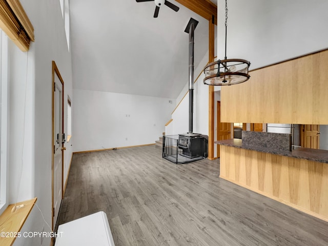 26839 S Talkeetna Spur Rd, Talkeetna, AK 99676 - unfurnished living room with a wood stove, ceiling fan, wood finished floors, high vaulted ceiling, and beamed ceiling