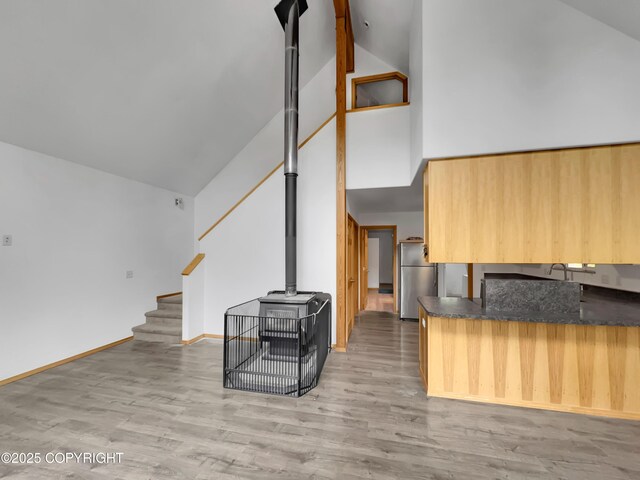26839 S Talkeetna Spur Rd, Talkeetna, AK 99676 - unfurnished living room featuring high vaulted ceiling, a wood stove, light wood-style floors, stairway, and baseboards