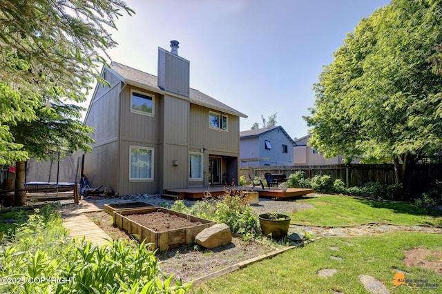 3941 Eric Cir, Anchorage, AK 99507 - back of property featuring a trampoline, a fenced backyard, a chimney, a vegetable garden, and a wooden deck