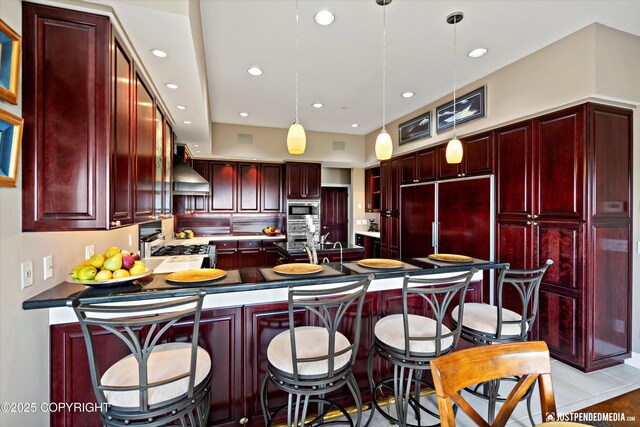 9900 Hillhaven Cir, Anchorage, AK 99507 - kitchen with dark brown cabinets, custom range hood, a peninsula, built in appliances, and recessed lighting