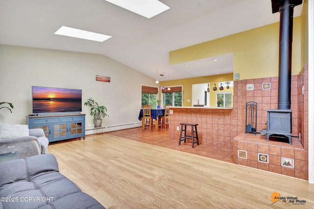 3868 Shannon Cir, Anchorage, AK 99508 - living area featuring a baseboard radiator, a wood stove, wood finished floors, vaulted ceiling, and a skylight