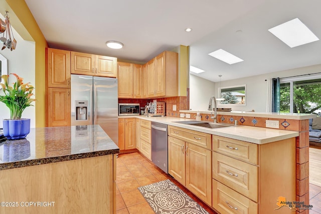 3868 Shannon Cir, Anchorage, AK 99508 - kitchen with a skylight, light brown cabinets, appliances with stainless steel finishes, a sink, and a peninsula