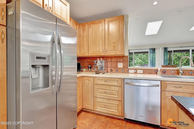 3868 Shannon Cir, Anchorage, AK 99508 - kitchen featuring appliances with stainless steel finishes, light brown cabinets, a sink, backsplash, and a skylight