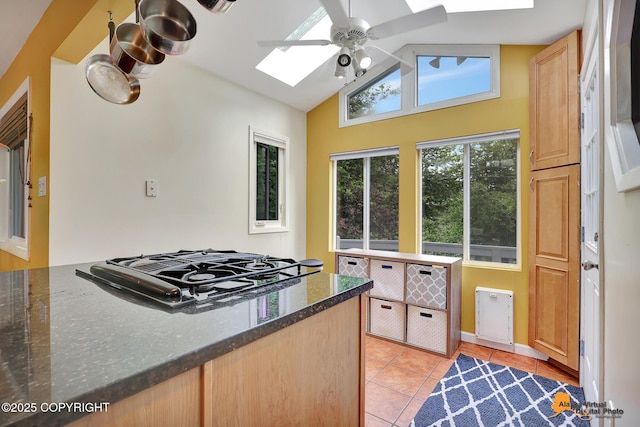 3868 Shannon Cir, Anchorage, AK 99508 - kitchen featuring a skylight, black gas cooktop, light tile patterned flooring, a ceiling fan, and vaulted ceiling