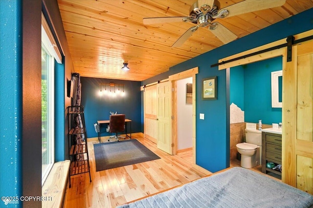 23069 Christiansen Lake Rd, Talkeetna, AK 99676 - bedroom with a barn door, wooden ceiling, a desk, connected bathroom, and wood finished floors