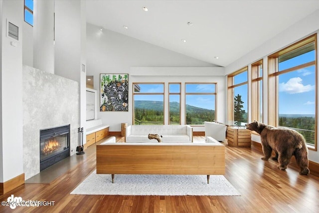 10500 Blackwolf Cir, Anchorage, AK 99507 - living area featuring a glass covered fireplace, wood finished floors, high vaulted ceiling, and recessed lighting
