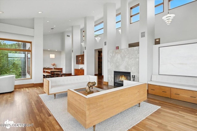 10500 Blackwolf Cir, Anchorage, AK 99507 - living area with a towering ceiling, plenty of natural light, light wood-type flooring, a glass covered fireplace, and recessed lighting