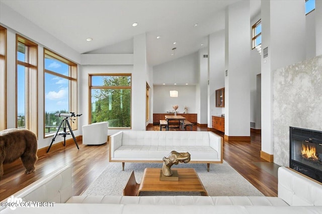 10500 Blackwolf Cir, Anchorage, AK 99507 - living area featuring wood finished floors, a glass covered fireplace, high vaulted ceiling, and recessed lighting