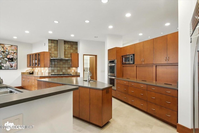 10500 Blackwolf Cir, Anchorage, AK 99507 - kitchen featuring stainless steel appliances, a center island with sink, wall chimney range hood, brown cabinets, and recessed lighting