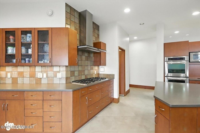 10500 Blackwolf Cir, Anchorage, AK 99507 - kitchen with wall chimney range hood, appliances with stainless steel finishes, tasteful backsplash, glass insert cabinets, and brown cabinetry