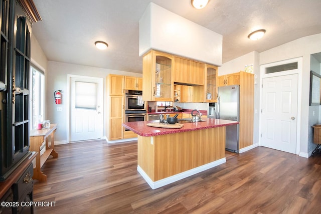 4530 Macalister Dr, Anchorage, AK 99502 - kitchen with stainless steel appliances, a center island, light brown cabinets, dark wood-type flooring, and glass insert cabinets