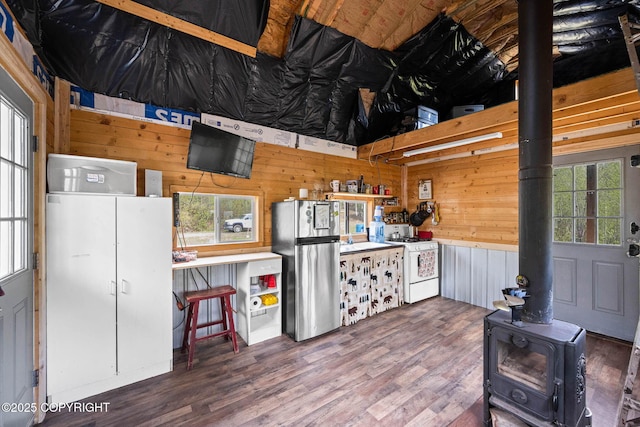 6360 Haystack Dr, Fairbanks, AK 99712 - kitchen with freestanding refrigerator, gas range gas stove, wood walls, a wood stove, and wood finished floors