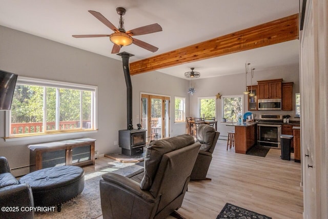 33426 Mid River Ave, Soldotna, AK 99669 - living area with a wood stove, beam ceiling, baseboard heating, light wood-type flooring, and ceiling fan