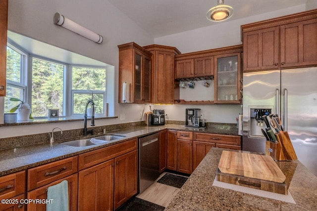 33426 Mid River Ave, Soldotna, AK 99669 - kitchen featuring appliances with stainless steel finishes, brown cabinetry, dark stone countertops, glass insert cabinets, and light wood finished floors