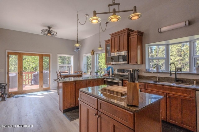 33426 Mid River Ave, Soldotna, AK 99669 - kitchen with stainless steel appliances, a peninsula, brown cabinetry, light wood-type flooring, and a center island