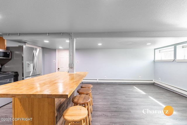 799 8th Ave, Fairbanks, AK 99701 - kitchen featuring wood counters, appliances with stainless steel finishes, wood finished floors, a kitchen breakfast bar, and recessed lighting