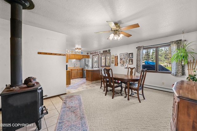 48160 Snowflake Ct, Soldotna, AK 99669 - dining space with baseboard heating, a wood stove, a ceiling fan, a textured ceiling, and light tile patterned floors