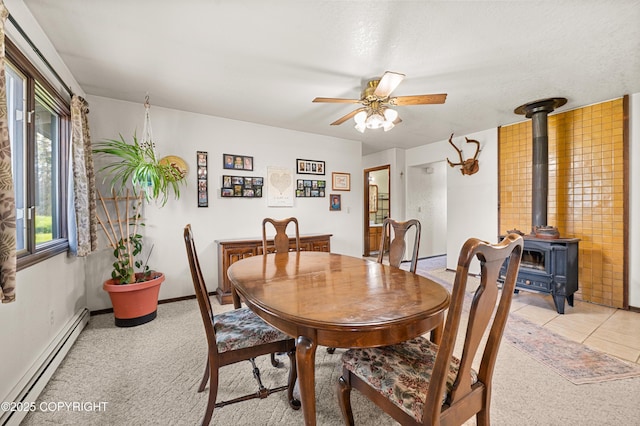 48160 Snowflake Ct, Soldotna, AK 99669 - dining space featuring baseboard heating, a wood stove, ceiling fan, and light colored carpet