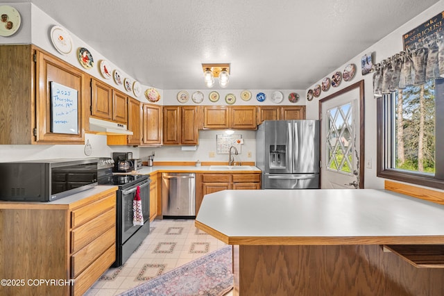 48160 Snowflake Ct, Soldotna, AK 99669 - kitchen with appliances with stainless steel finishes, under cabinet range hood, light countertops, brown cabinets, and a peninsula