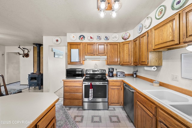 48160 Snowflake Ct, Soldotna, AK 99669 - kitchen with appliances with stainless steel finishes, under cabinet range hood, light countertops, a textured ceiling, and brown cabinetry