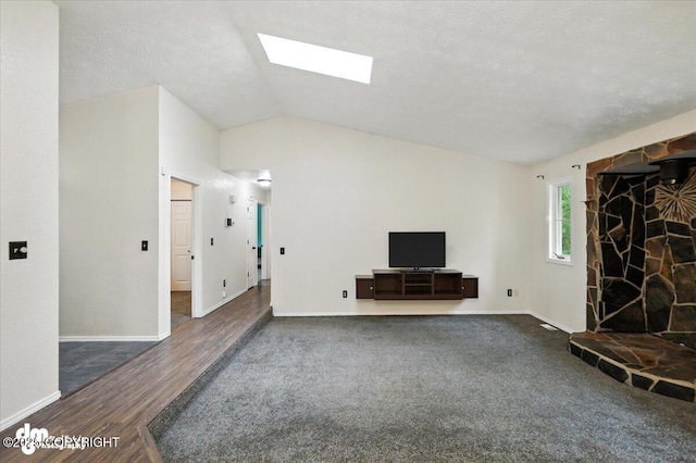 1940 E Caribou Loop, Wasilla, AK 99654 - unfurnished living room featuring vaulted ceiling, dark wood-style floors, a skylight, a fireplace, and a textured ceiling
