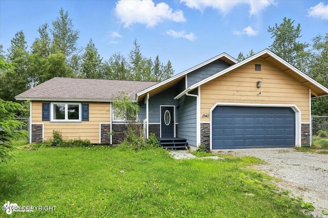 1940 E Caribou Loop, Wasilla, AK 99654 - view of front of home with stone siding, gravel driveway, an attached garage, and a front lawn