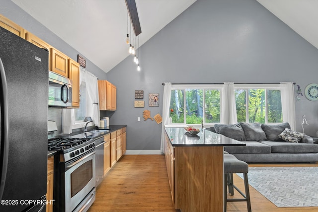 41167 Witman Ct, Soldotna, AK 99669 - kitchen featuring stainless steel appliances, high vaulted ceiling, dark countertops, a kitchen bar, and a sink