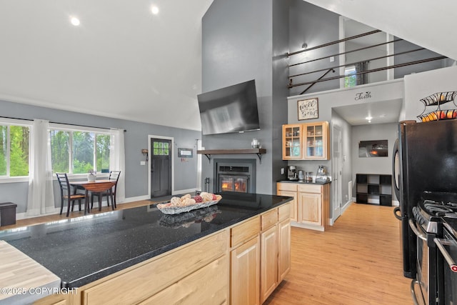 41167 Witman Ct, Soldotna, AK 99669 - kitchen featuring light brown cabinetry, high vaulted ceiling, light wood-style flooring, a glass covered fireplace, and glass insert cabinets