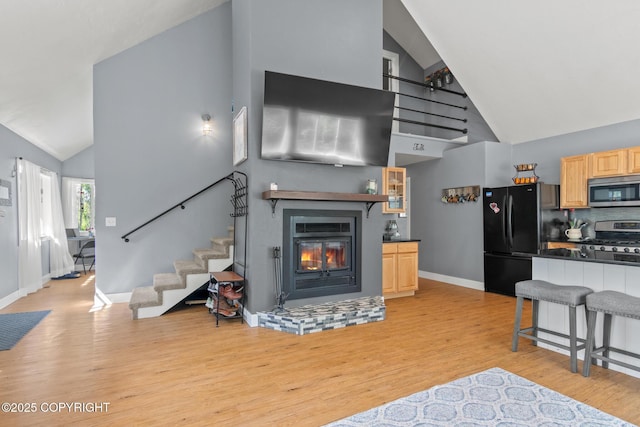 41167 Witman Ct, Soldotna, AK 99669 - living room with high vaulted ceiling, stairway, a glass covered fireplace, light wood-style floors, and baseboards