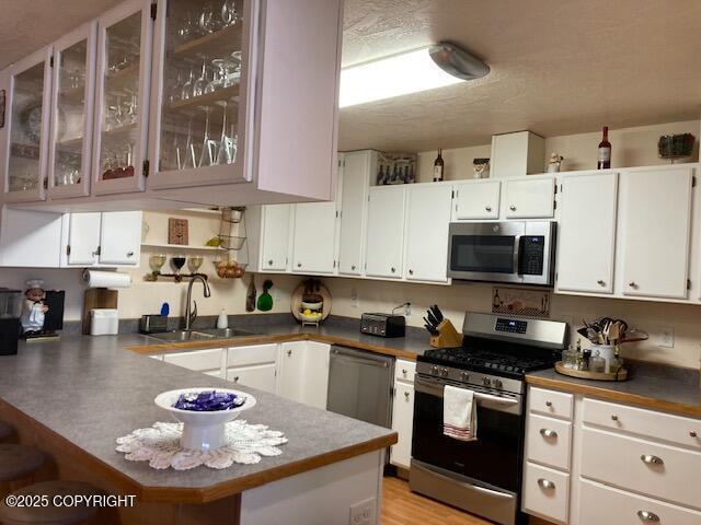 50470 Maranatha Ln, Nikiski/North Kenai, AK 99611 - kitchen featuring stainless steel appliances, a peninsula, white cabinetry, and glass insert cabinets