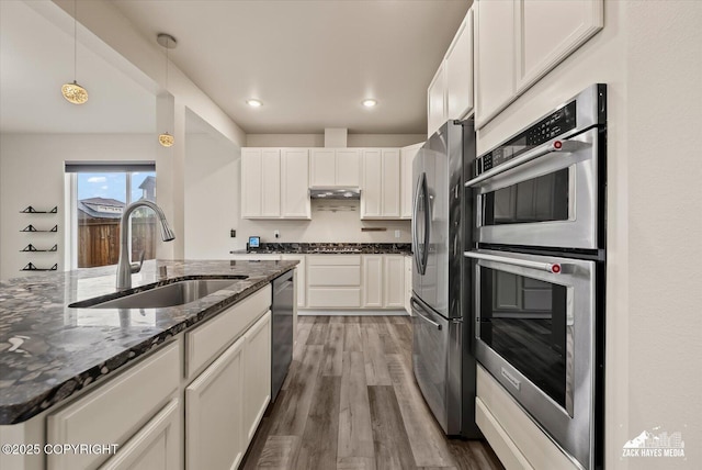 2987 Morgan Loop, Anchorage, AK 99516 - kitchen with appliances with stainless steel finishes, wood finished floors, white cabinets, dark stone counters, and decorative light fixtures