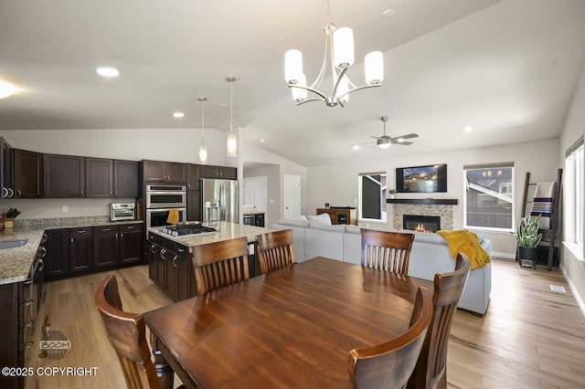 13378 Rosser Dr, Eagle River, AK 99577 - dining area featuring vaulted ceiling, a ceiling fan, light wood-style flooring, a fireplace, and a chandelier