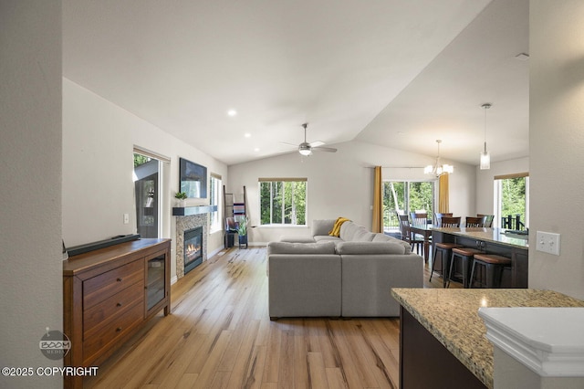 13378 Rosser Dr, Eagle River, AK 99577 - living area with light wood-type flooring, a glass covered fireplace, vaulted ceiling, a ceiling fan, and a chandelier