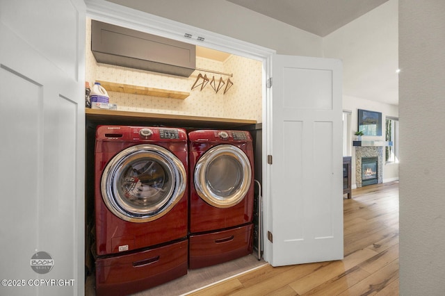 13378 Rosser Dr, Eagle River, AK 99577 - laundry room featuring washer and clothes dryer, wood finished floors, and a glass covered fireplace