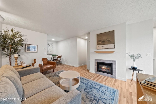 943 E 12th Ave # 6, Anchorage, AK 99501 - living room with light wood-style flooring, a textured ceiling, baseboards, a tile fireplace, and recessed lighting