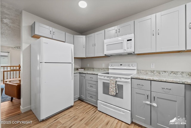 943 E 12th Ave # 6, Anchorage, AK 99501 - kitchen with white appliances, gray cabinets, light wood finished floors, and light stone counters