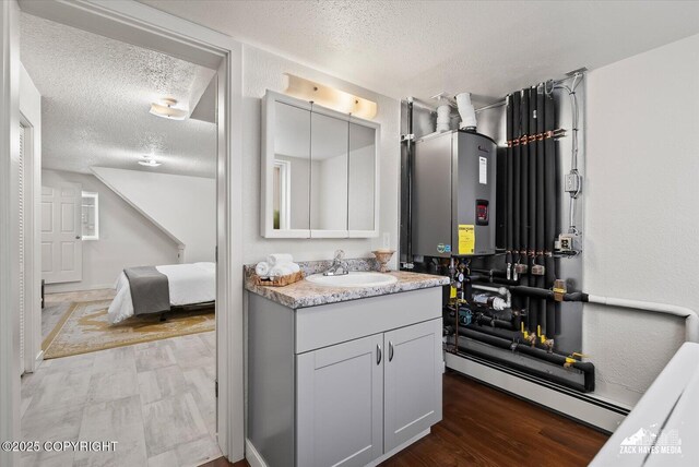943 E 12th Ave # 6, Anchorage, AK 99501 - bathroom featuring a textured ceiling, tankless water heater, vanity, a baseboard radiator, and wood finished floors